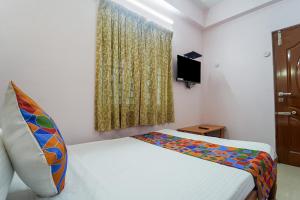 a small bedroom with a bed and a tv at FabHotel Terra in Chennai