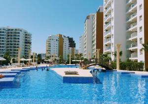 a large swimming pool in a city with tall buildings at Charming 1+1 Caesar Resort Apartment in Trikomo