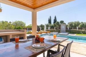 an outdoor dining table with chairs and a pool at Paris Family Villa! in Makhairádhon