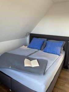 ein Bett mit zwei blauen Kissen und einem Buch darauf in der Unterkunft Casa Marcu Wohnung 1 OG in Landkirchen