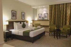 een hotelkamer met een groot bed en 2 stoelen bij The Parisian Hotel in Beiroet