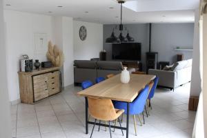 a living room with a wooden table and blue chairs at Maison jardin proximité Bayeux, Arromanches in Ranchy