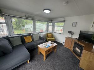 sala de estar con sofá y TV en Riverview Caravan, en Briery Yards