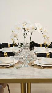 uma mesa com pratos e um vaso com flores brancas em Luxury Beach Apartment em Ras al-Khaimah