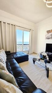 a living room with a leather couch and a large window at Beach Apartment in Ras al Khaimah