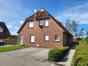 a brick house with white windows on a street at FeWo Poststr. 9 Norddeich in Norddeich