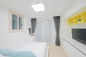 a white room with a bed and a television at E7 YANGYANG JUKDO in Yangyang