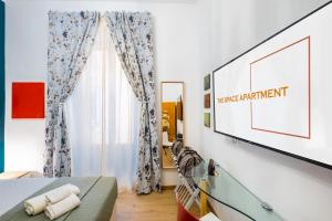 una camera da letto con una TV a schermo piatto su una parete di The Space Rooms a Roma