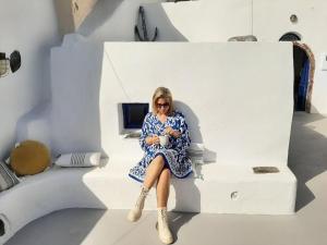 una mujer con un vestido azul sentada en una silla en Magic View Canava, en Oia