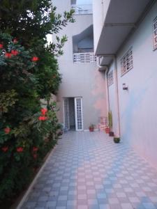 a walkway leading to a white building with red flowers at Ben arous one in Ben Arous