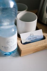 a bottle of water sitting on a wooden plate next to a cup at Pod Sową in Sokolec