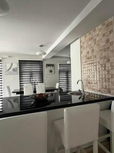 a kitchen with a black counter and white chairs at Diamond Hotel & Restaurant in Ulcinj