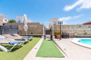 un patio trasero con tumbonas y piscina en Cozy villa in Madroñal de Fañabe with large private pool, en Adeje