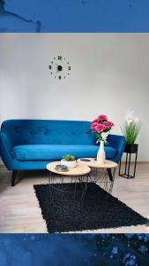 a living room with a blue couch and two tables with flowers at Apartman Luxe Victoria in Zagreb