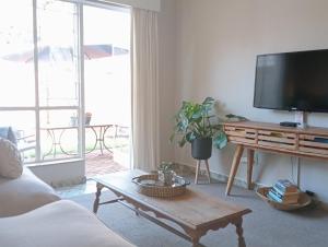 ein Wohnzimmer mit einem TV und einem Couchtisch in der Unterkunft Willows Garden Cottage in Pretoria