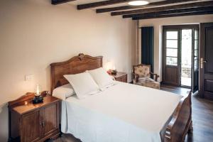 a bedroom with a large white bed and a chair at casa rural O lar do San Paio in Erboedo