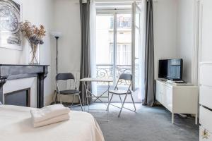 a bedroom with a bed and a tv and a table and chairs at Montmartre Apartments - Degas in Paris
