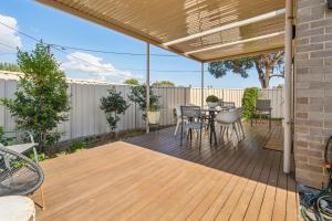 a patio with a wooden deck with a table and chairs at Enfield Executive in Gepps Cross