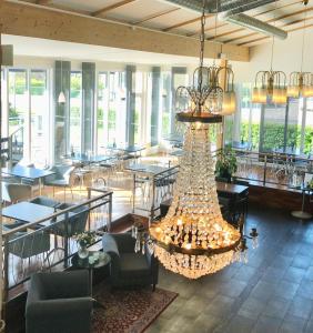 a large chandelier in a restaurant with tables and chairs at Arena Hotell in Vänersborg