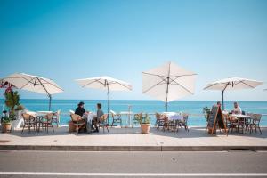 a group of people sitting at tables with umbrellas on the beach at Le COQ Edouard VII - Parking - Proche mer in Menton