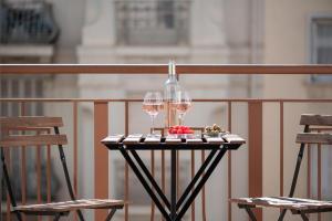 a table with two glasses of wine and two chairs at Le COQ Edouard VII - Parking - Proche mer in Menton
