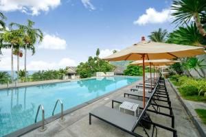 a swimming pool with chairs and an umbrella at Andamantra Resort and Villa Phuket - SHA Extra Plus in Patong Beach