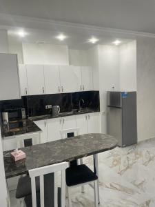 a kitchen with white cabinets and a table and a refrigerator at Apartment in centre of Yerevan in Yerevan