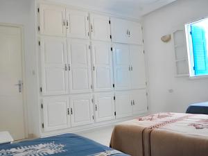 a white bedroom with white cabinets and a bed at 2 bedrooms apartement with enclosed garden and wifi at Djerba Midoun 1 km away from the beach in Aghīr