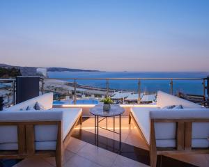 - un balcon avec deux chaises et une table donnant sur l'océan dans l'établissement Trypiti Resort Blue Dream Palace and Hive Water Park, à Limenaria