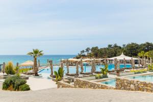 a resort with a pool and the ocean in the background at Trypiti Resort Blue Dream Palace and Hive Water Park in Limenaria