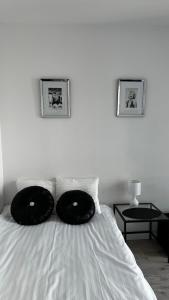 a white bed with two black pillows on it at Primo Fabryczna Studio in Łódź