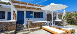 a white house with a bench and an umbrella at Diana's Luxury Suites in Kithnos