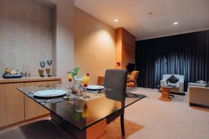 Surabaya Suites Hotel Powered by Archipelago في سورابايا: غرفة معيشة مع طاولة وغرفة طعام