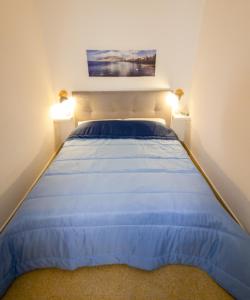 um quarto com uma cama com lençóis azuis e 2 candeeiros em Attracco Apartment em Trapani