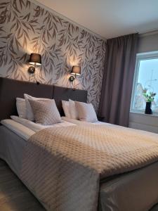 a bedroom with a large bed with two lamps on the wall at Arena Hotell in Vänersborg