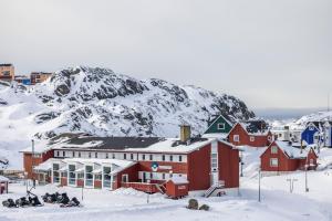 um grupo de pessoas sentadas na neve em frente a uma montanha em HOTEL SØMA Sisimiut em Sisimiut