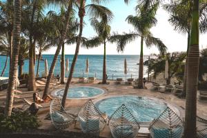 uma piscina com palmeiras e uma praia em Hotel Fariones em Puerto del Carmen