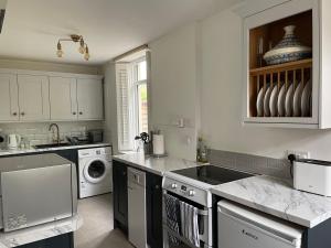 a white kitchen with a sink and a dishwasher at Victorian cottage overlooking the Plym Valley in Bickleigh