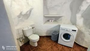 a white bathroom with a toilet and a washing machine at Casa Cueva Barranco Hondo in Gáldar
