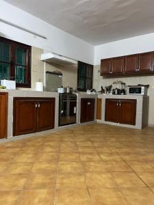 a large kitchen with brown cabinets and a wooden floor at Résidence Gabrielle in São Tomé