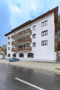 a white building with a car parked in front of it at Alpin Clabucet Studio in Predeal
