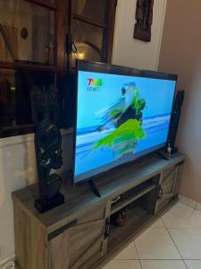 uma televisão de ecrã plano em cima de um centro de entretenimento em Résidence Gabrielle em São Tomé
