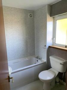 a bathroom with a white tub and a toilet and a sink at Alba, Beach Front Close to Restaurant in Lamlash