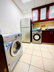 een keuken met een wasmachine en een koelkast bij The Aero Vacation Homes in Dubai