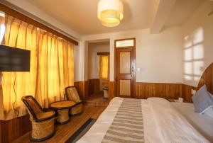 a bedroom with a bed and two chairs in it at Drifters Inn - The Hidden Tribe in Manāli