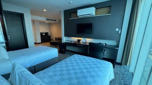a hotel room with two beds and a desk at Swiss-Belhotel Balikpapan in Balikpapan
