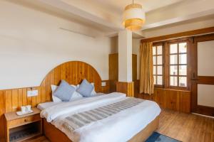 een slaapkamer met een groot bed met een houten hoofdeinde bij Drifters Inn - The Hidden Tribe in Manāli