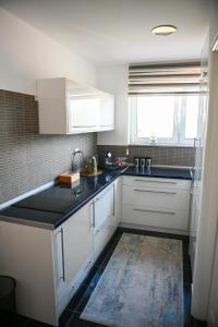 uma cozinha com armários brancos e um balcão preto em Prestige Apartment Teslic II em Teslic