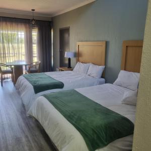 una habitación de hotel con dos camas y una mesa en Middelburg Country Club, en Middelburg