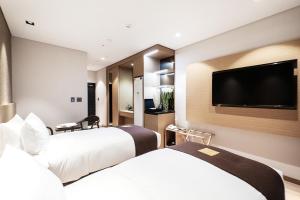 a hotel room with two beds and a flat screen tv at Intrada Icheon Hotel in Icheon